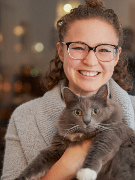 Hannah smiles while holding a very fluffy gray cat.