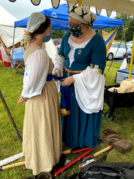 Emily and another historical reenactor talk while in period dress at an event 