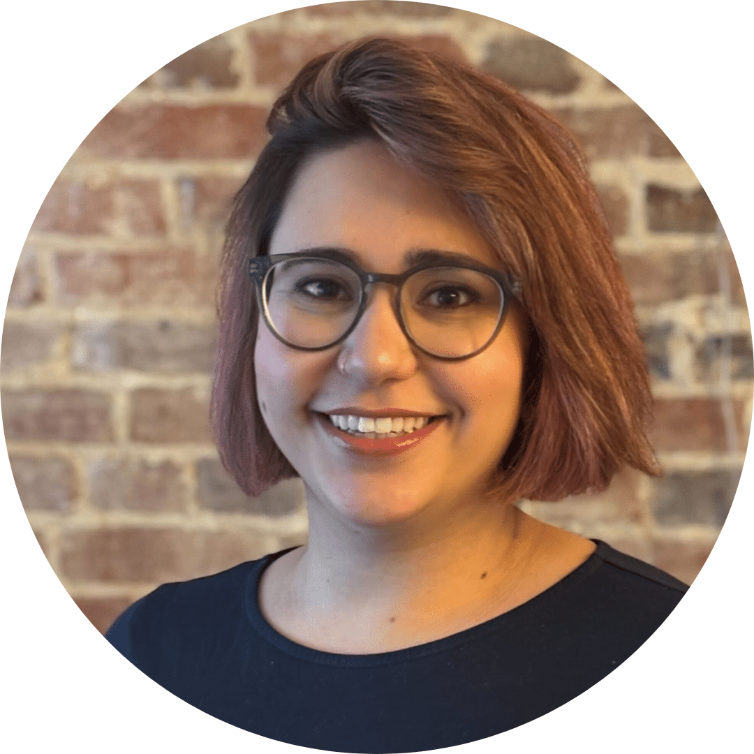 Noa Nir, wearing glasses, in front of a brick wall.