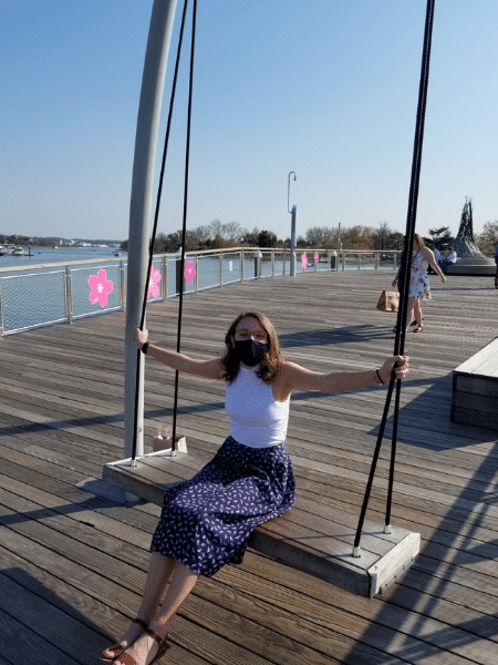 Same sits on a very large swing in the middle of a boardwalk.