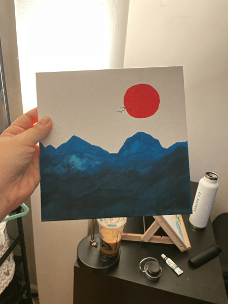 A painting Yaniza made with blue abstract mountains and a red moon or sun.