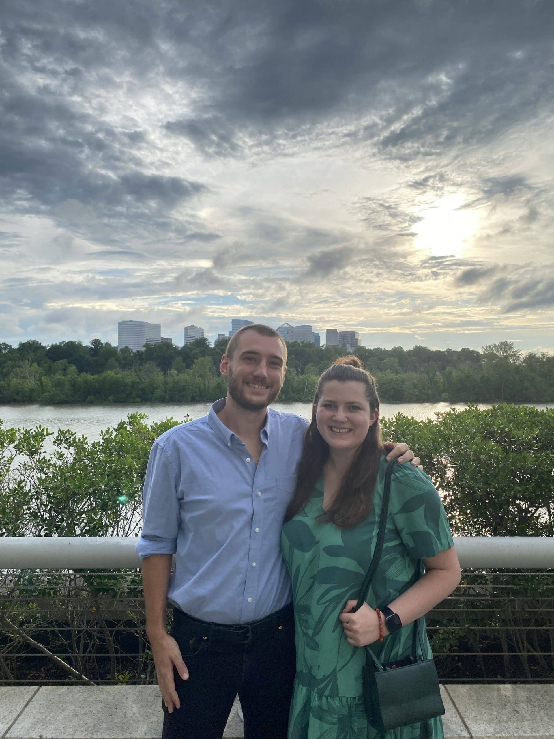 Samuel and his girlfriend in front of a river with a city skyline on the other side