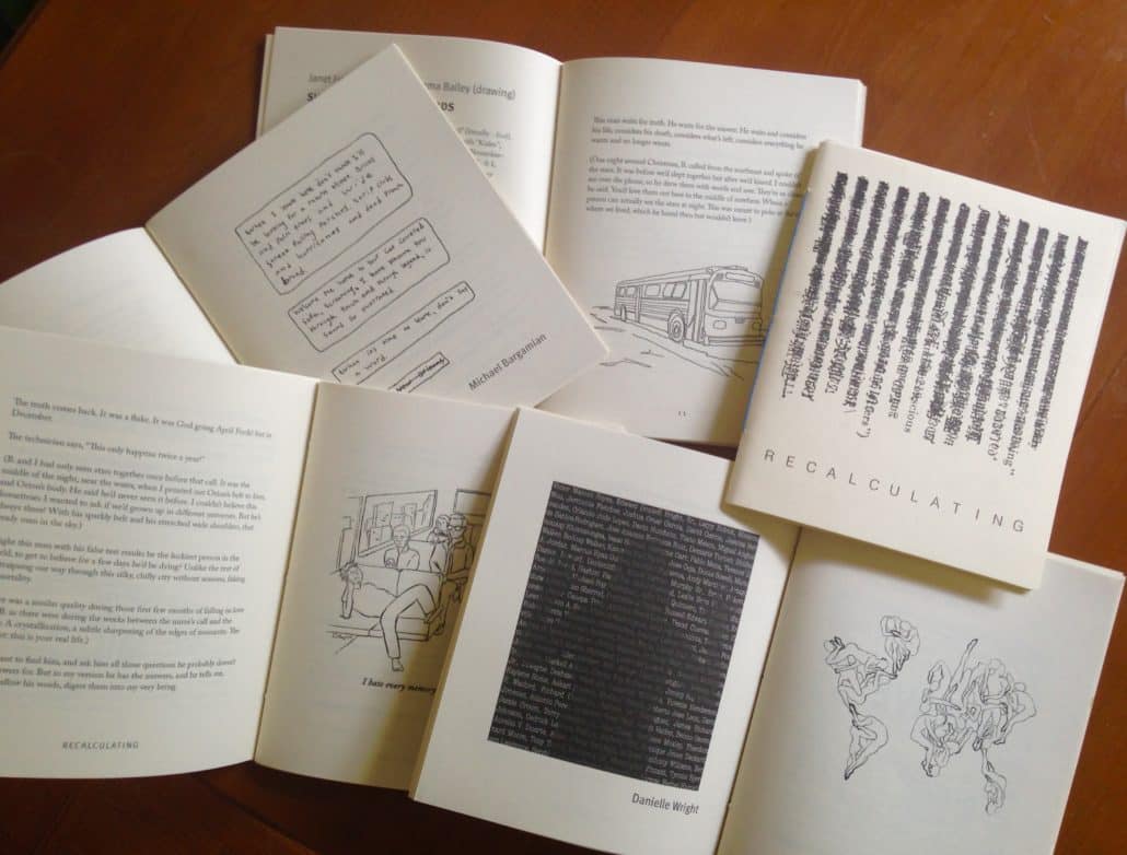 A pile of zines printed on white paper with text, illustration, and comics sit on a wooden table.