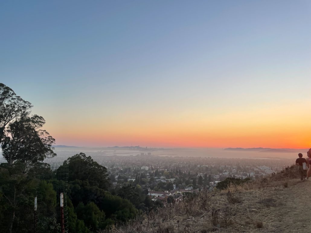The sun sets over the Bay Area, viewed from high elevation overseeing a developed area. 