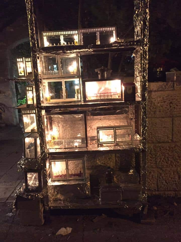 Menorahs lit and placed outdoors in stacked glass cases. Photo taken by Rabbi Ilana in Jerusalem, 2016. 