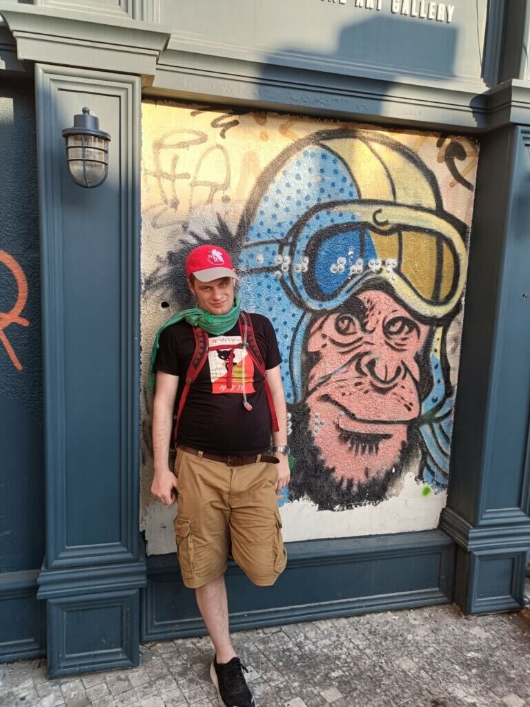 David poses with street art, a monkey in a motorcycle helmet. 