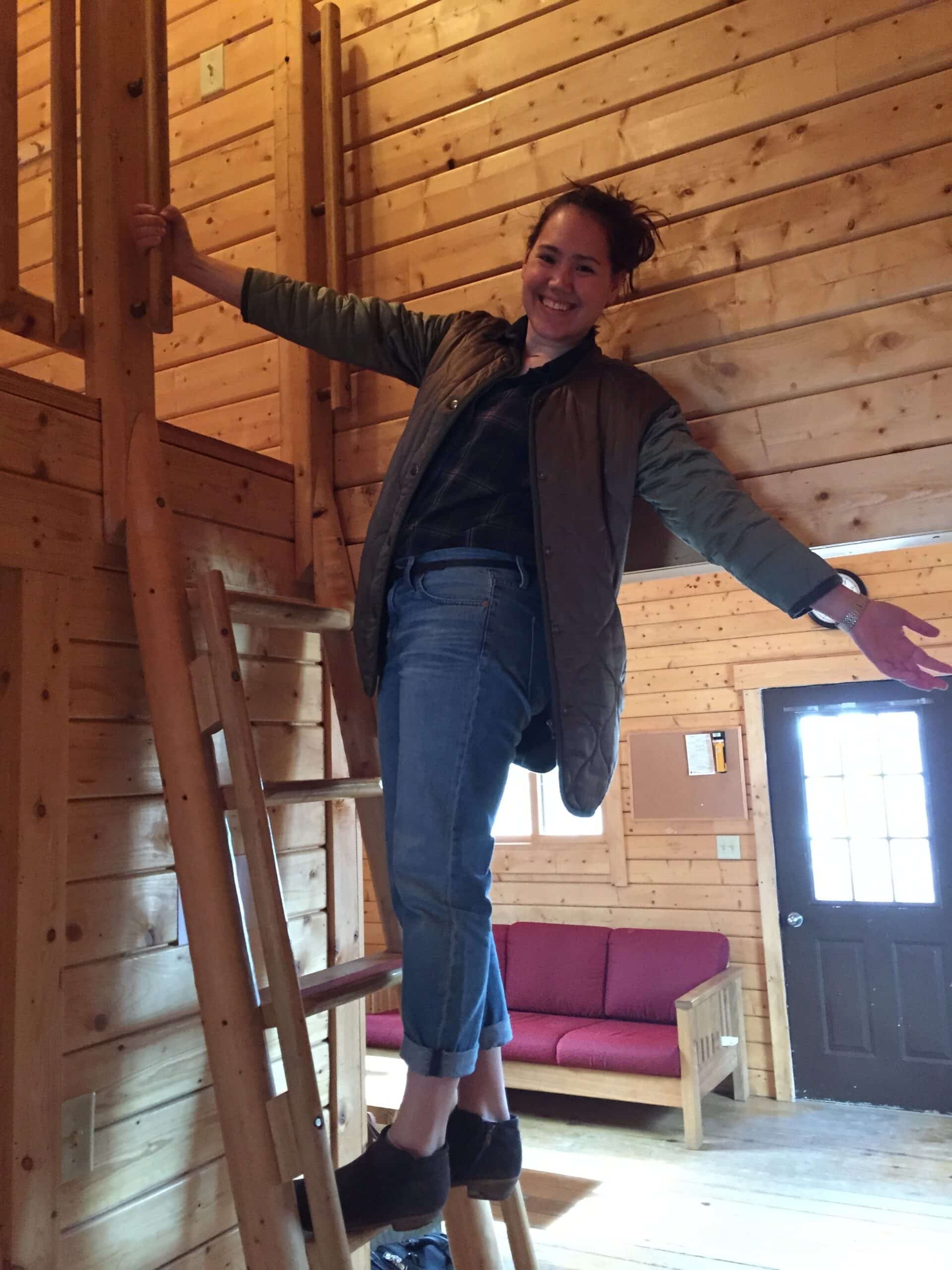 Jackie hangs off a ladder inside a cabin at a Gather retreat. 