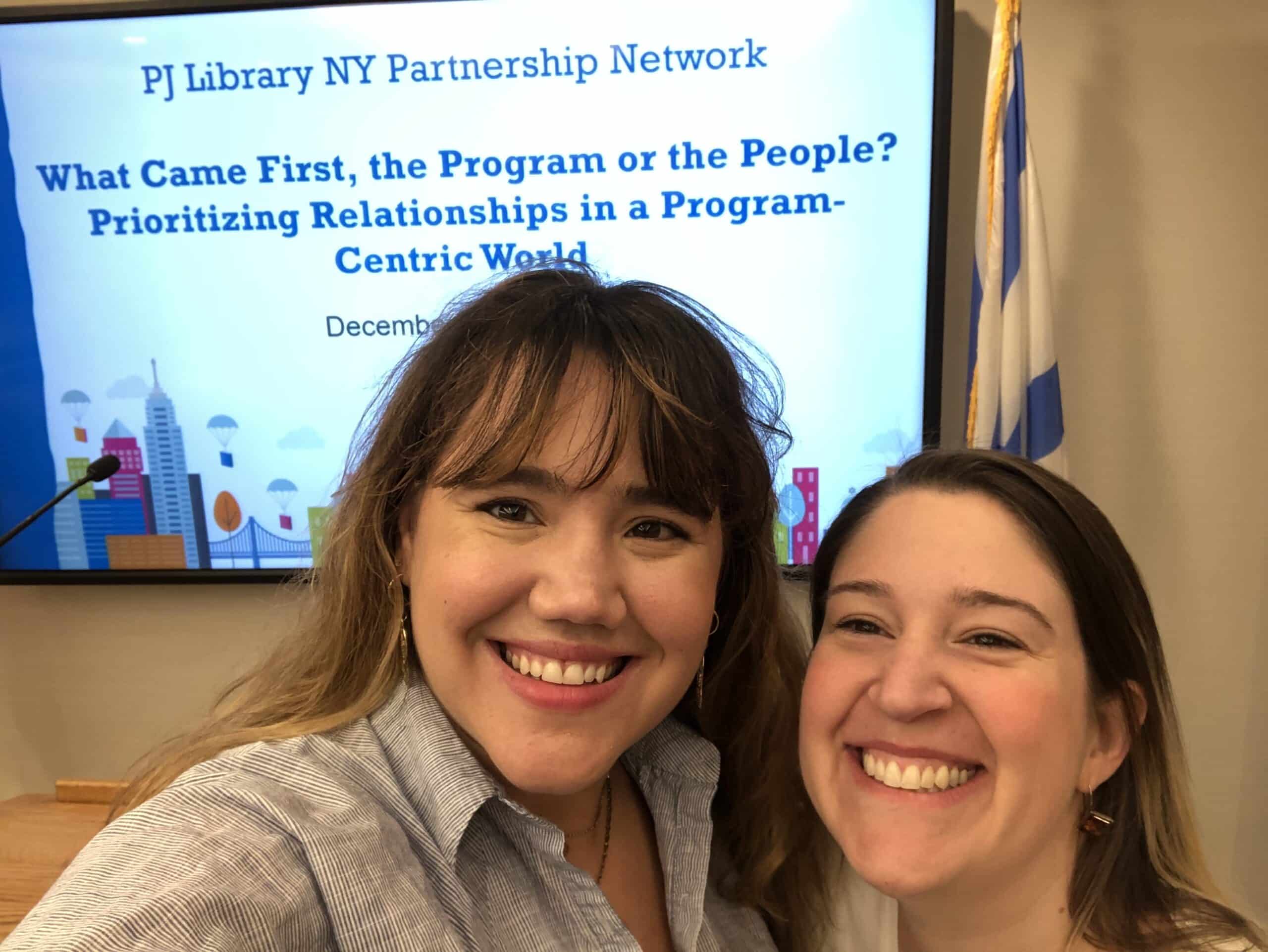 Jackie and Rachel take a selfie in front of a powerpoint presentation on relational engagement.