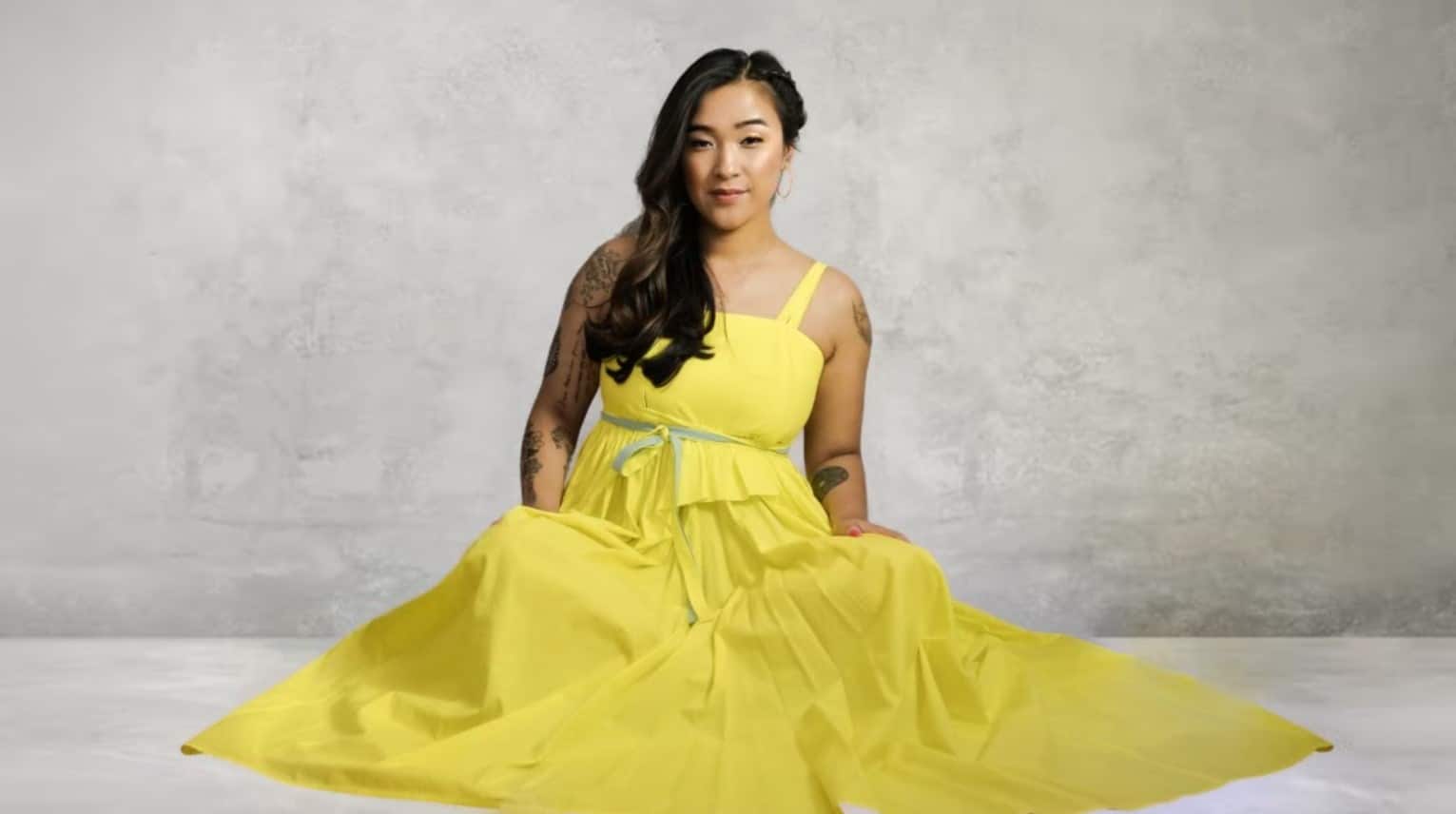 Liz sits in a yellow gown.