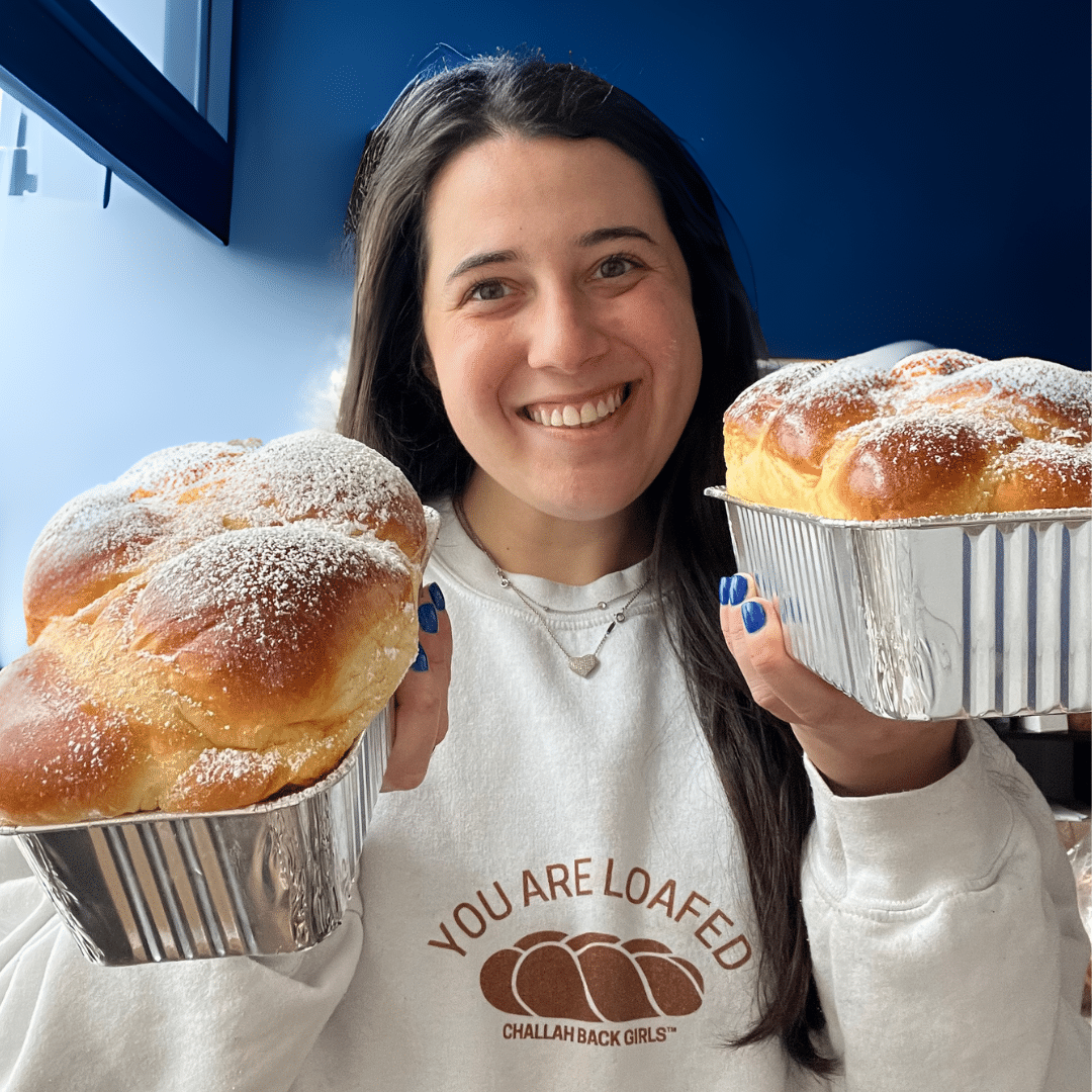 Sara holding two loaves of challah. 