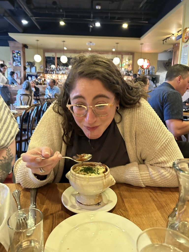 Jackie enthusiastically eats french onion soup. 