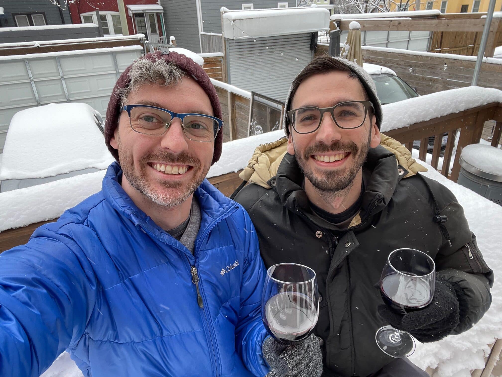 Nathan and his partner sip wine on a snowy deck.