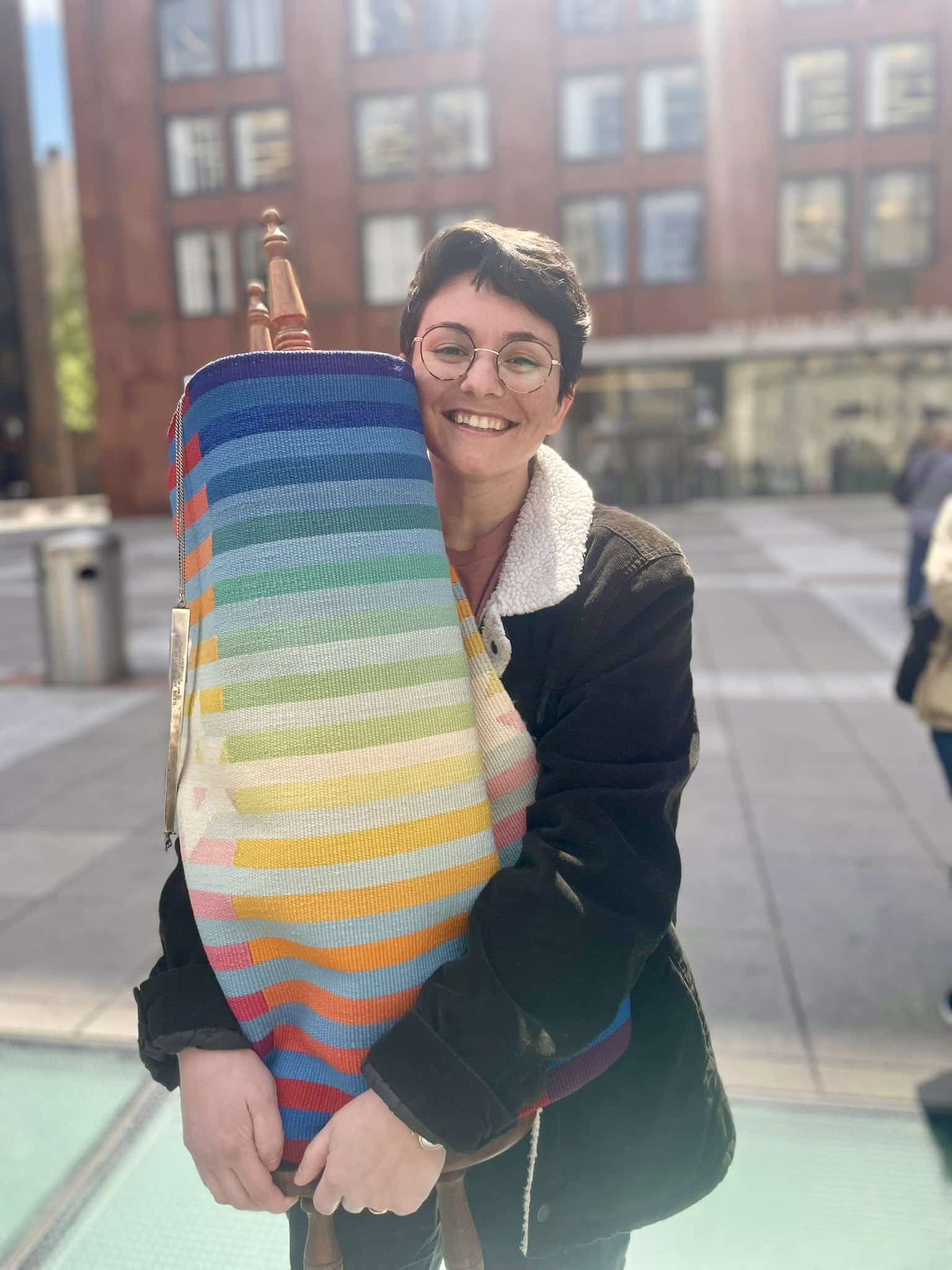 Ze'evi embraces a large, rainbow-wrapped scroll. 