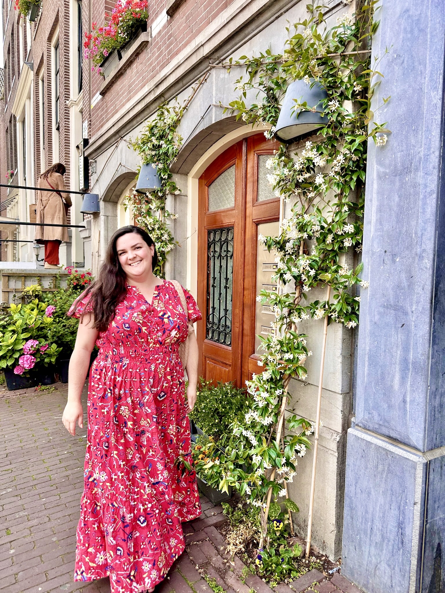 Sarah in a red dress in front of a vine-covered door.