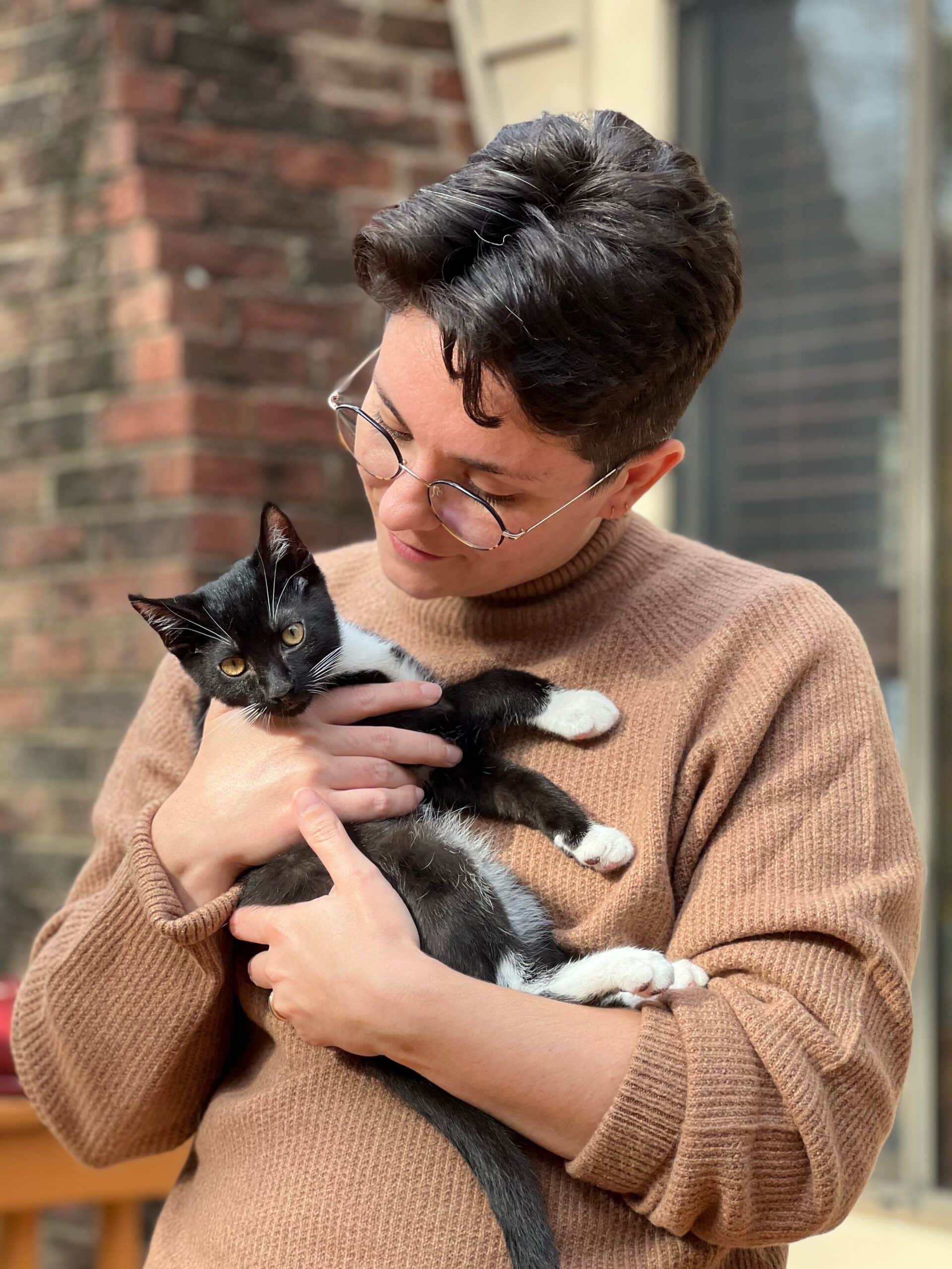 Ze'evi holds a black and white kitten.