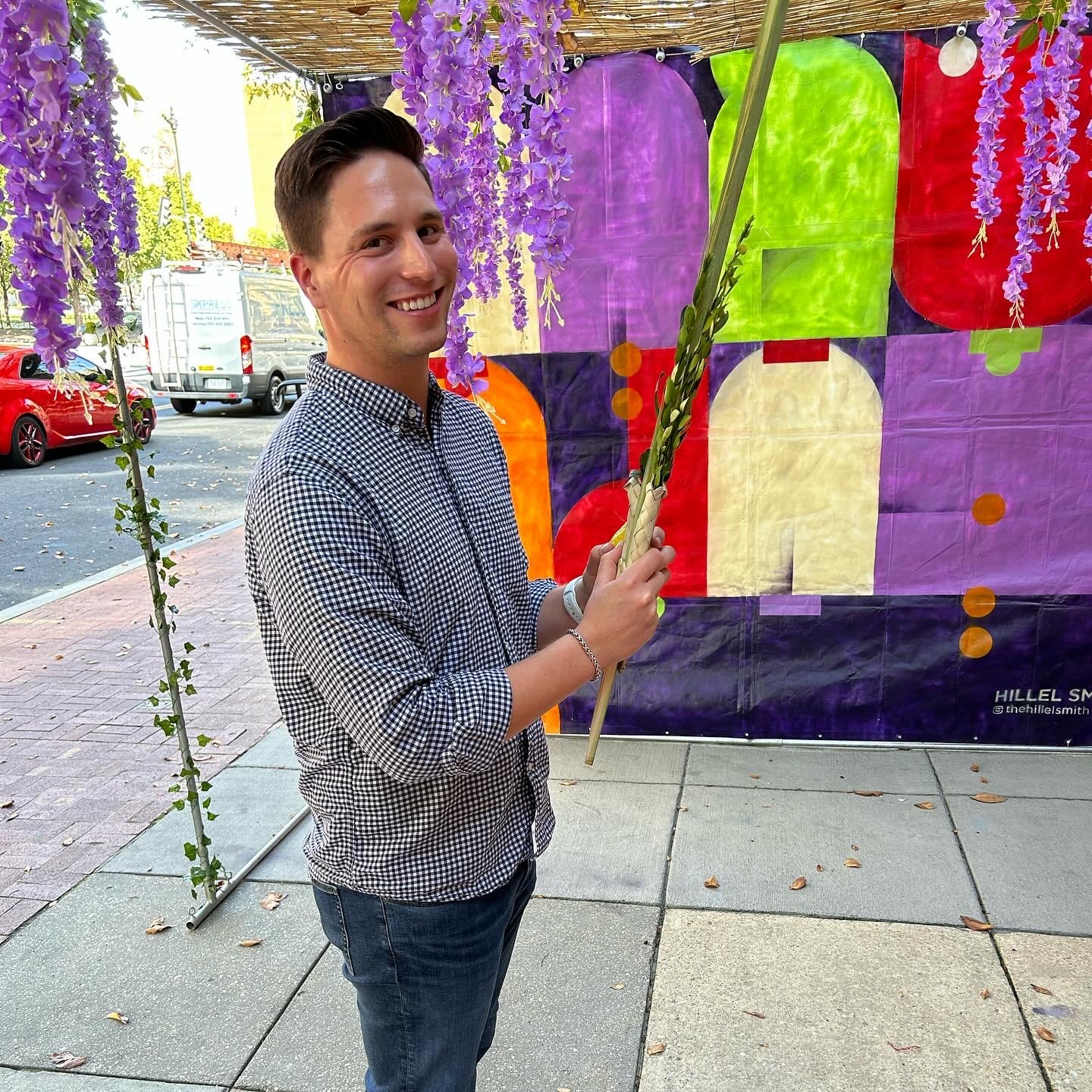 Aaron holds a lulav under a sukkah. 