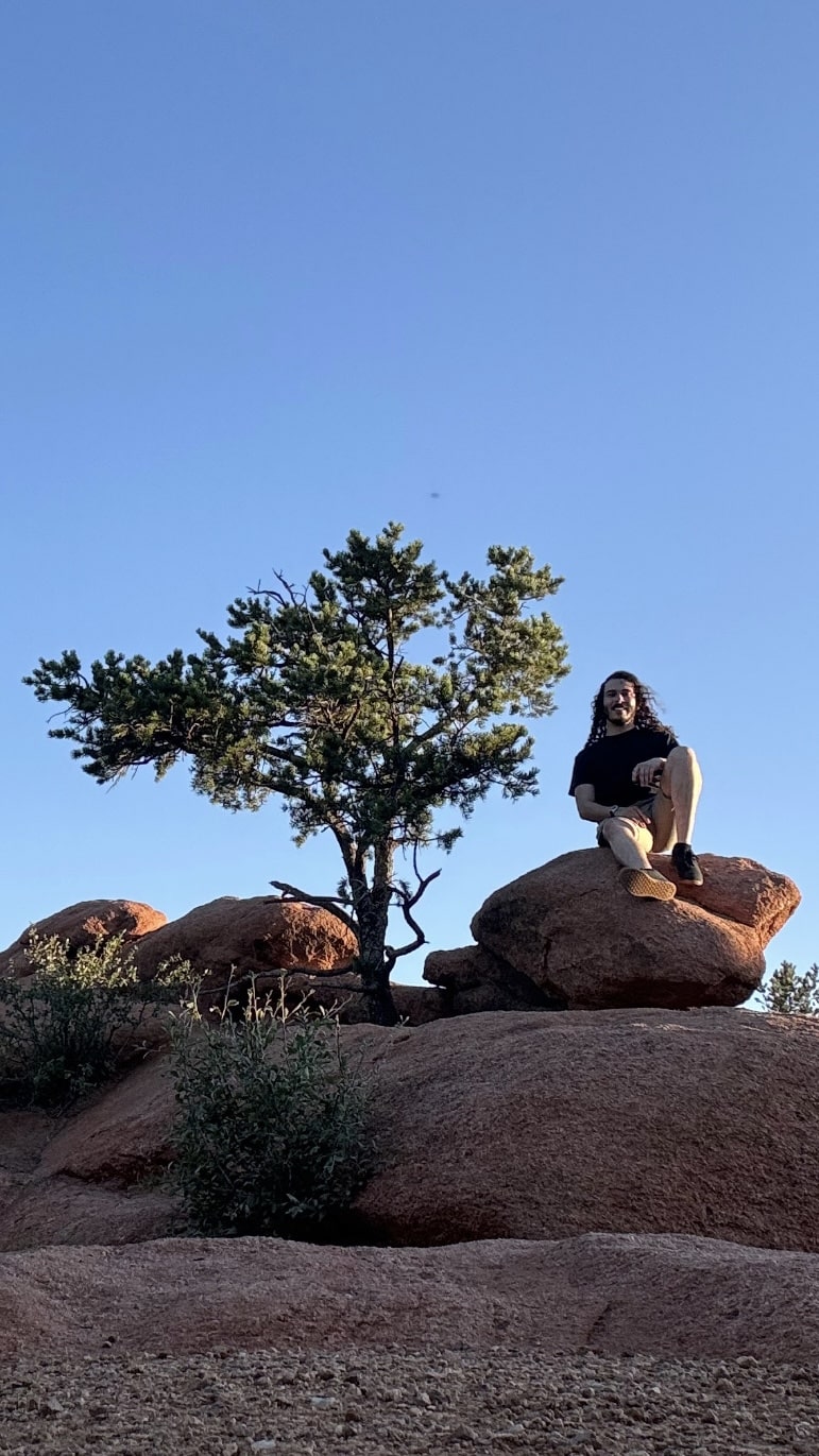 Eli sits on a desert rock.