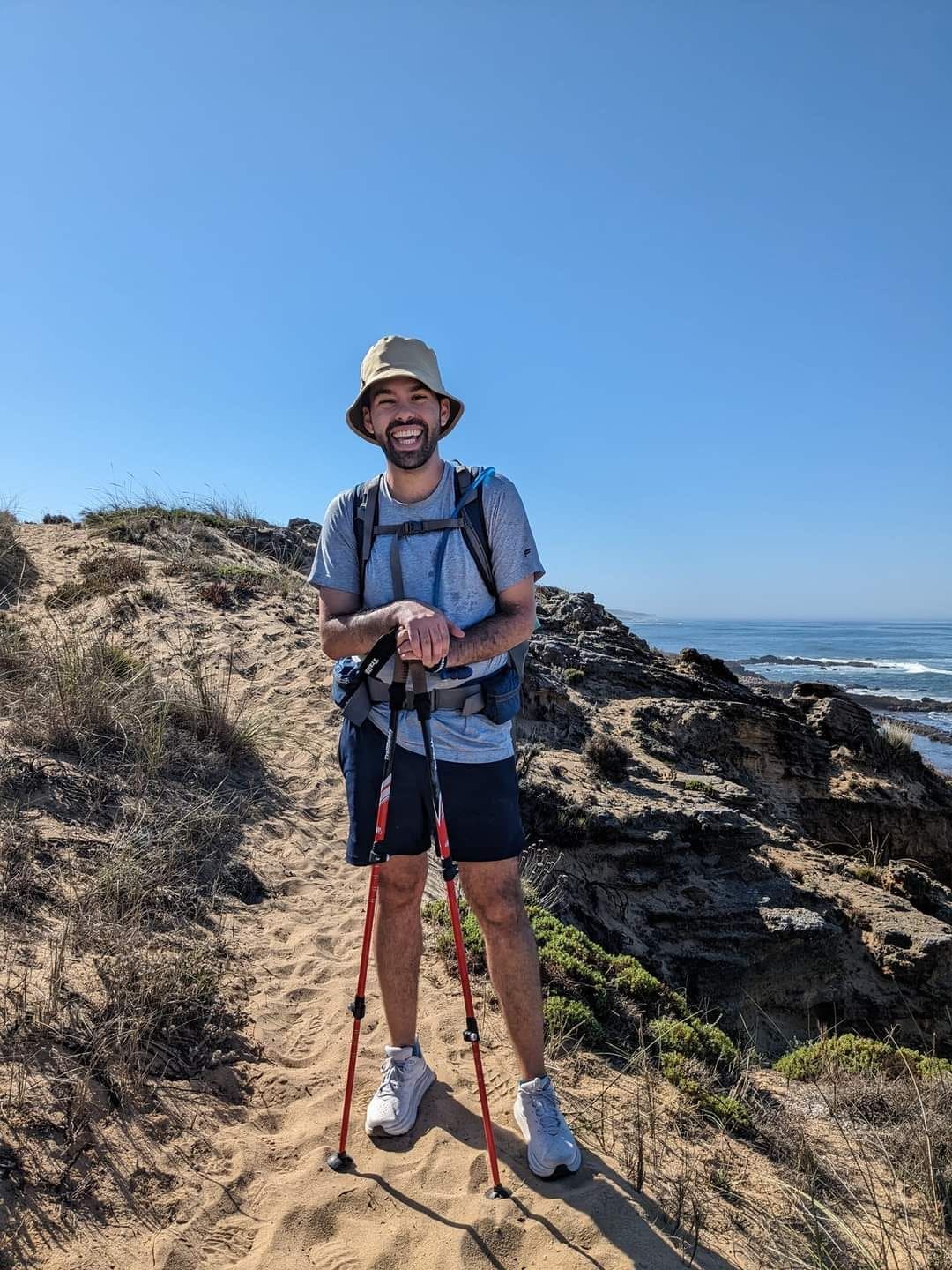 Eric with a walking stick, wearing a bucket hat.