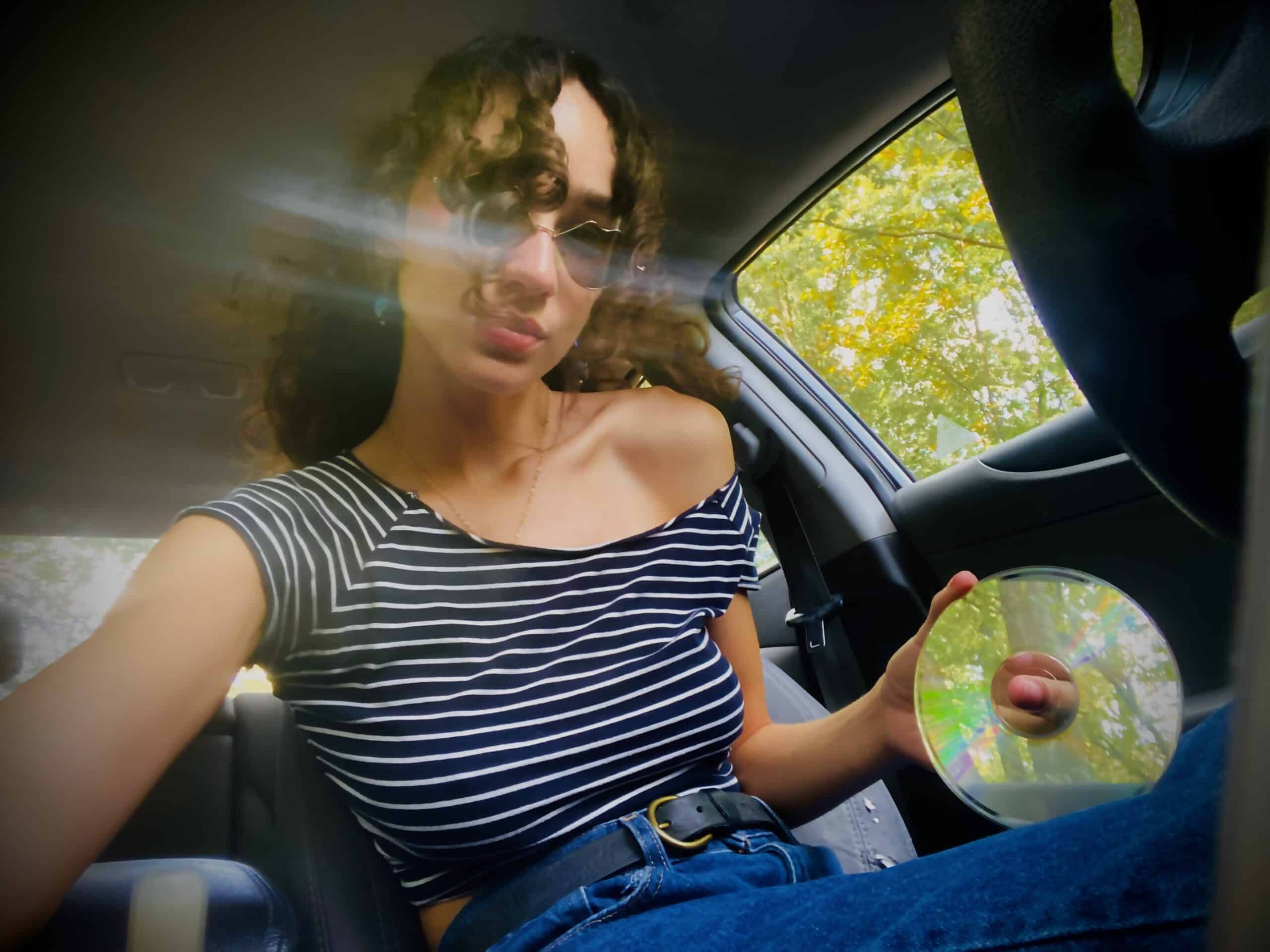 Angelina in her car holding a CD.