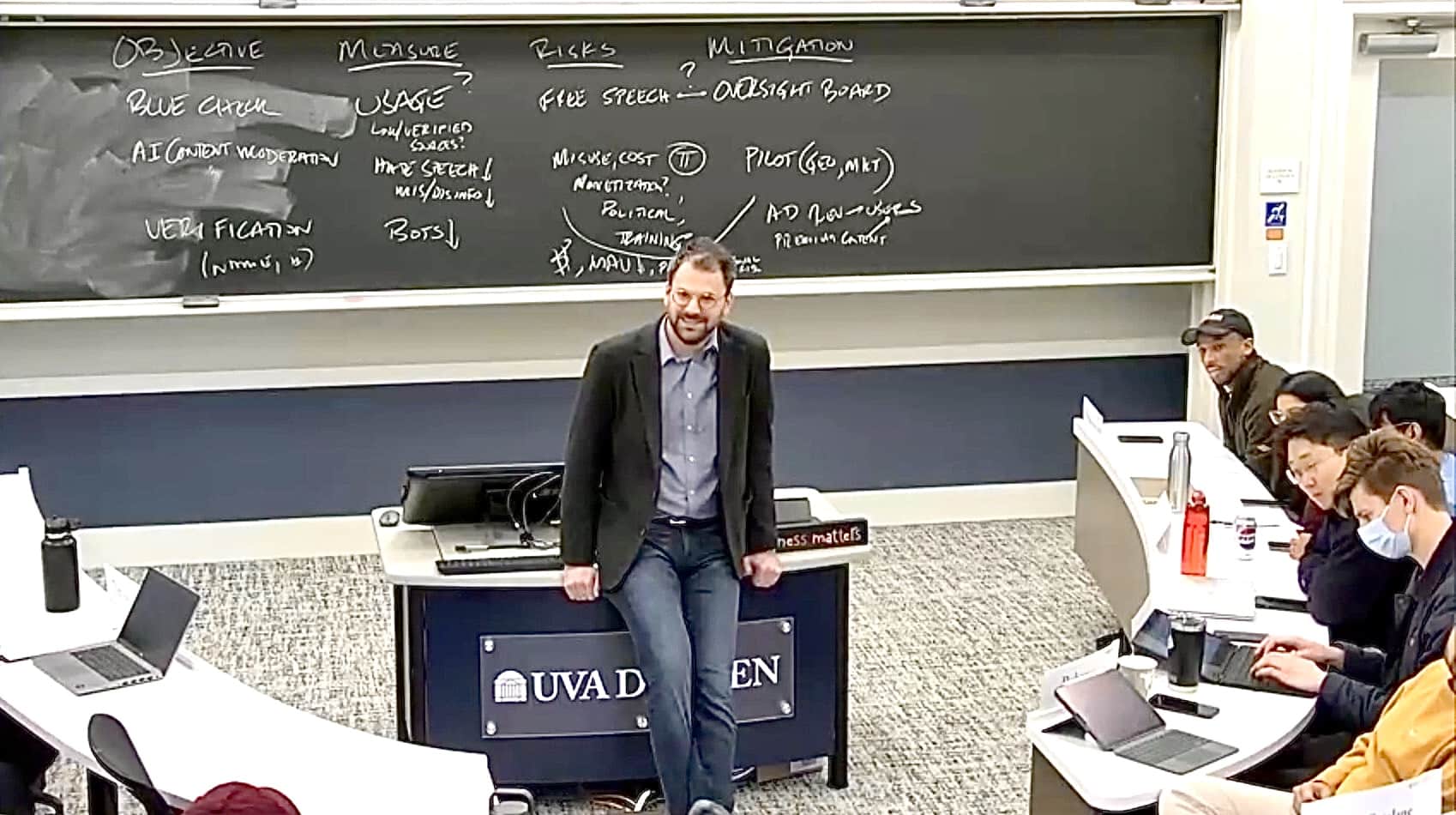 Ben leaning on a desk while teaching.