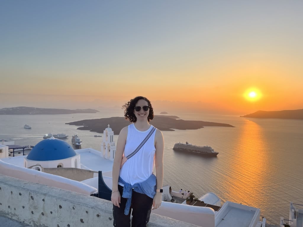 Ronit at sunset near a body of water.