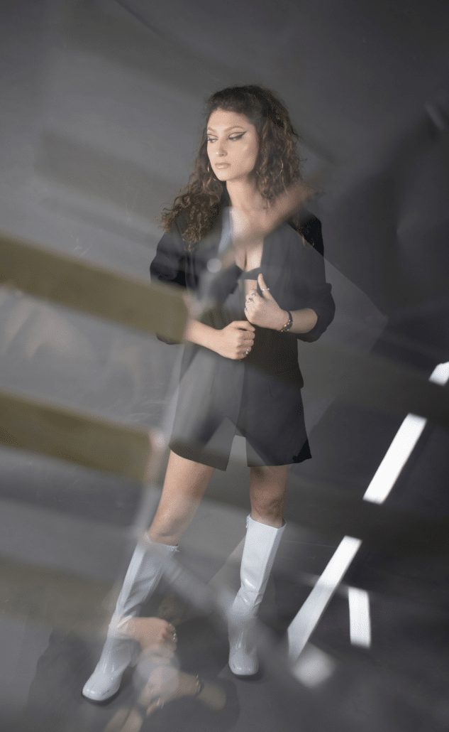 Leah in a black dress and high silver boots.