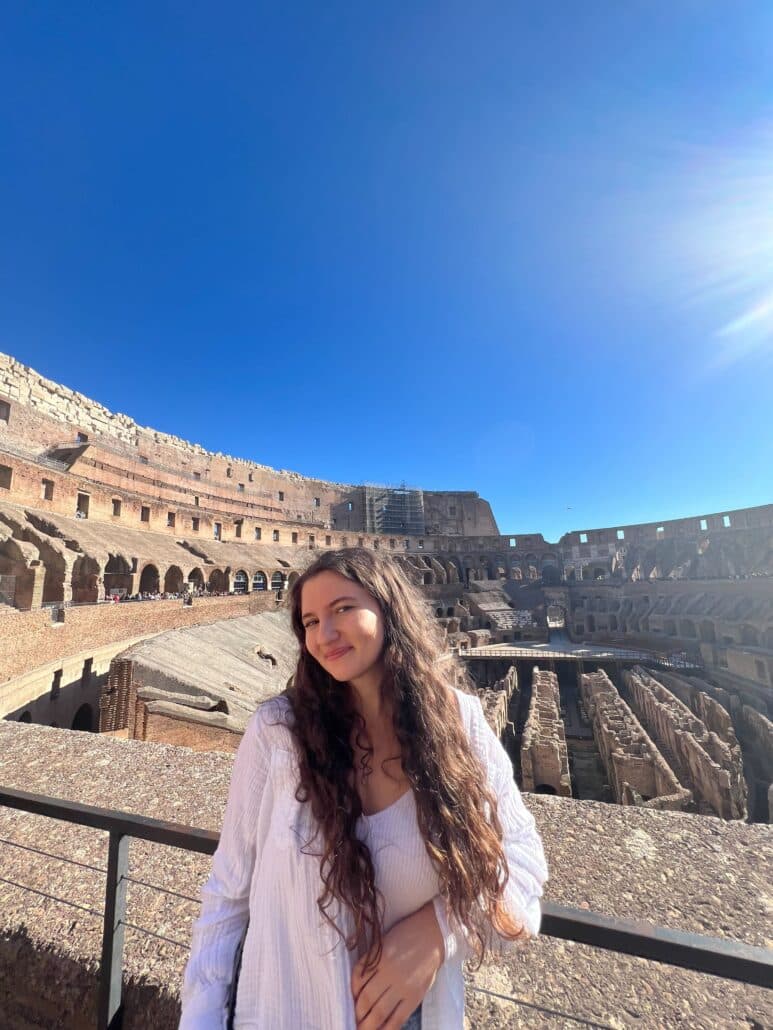 A young woman under a blue sky at the Coliseum.