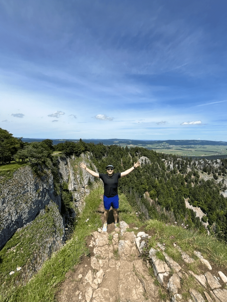 Adam on a ridge above a forest.