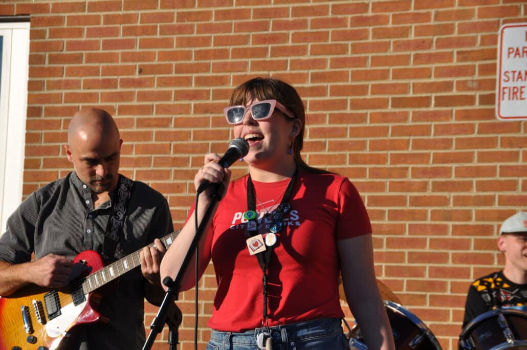 Claire singing into a microphone outdoors.