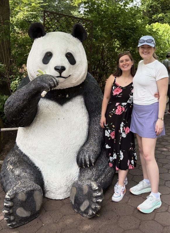Hally at the zoo with a woman and a panda statue.