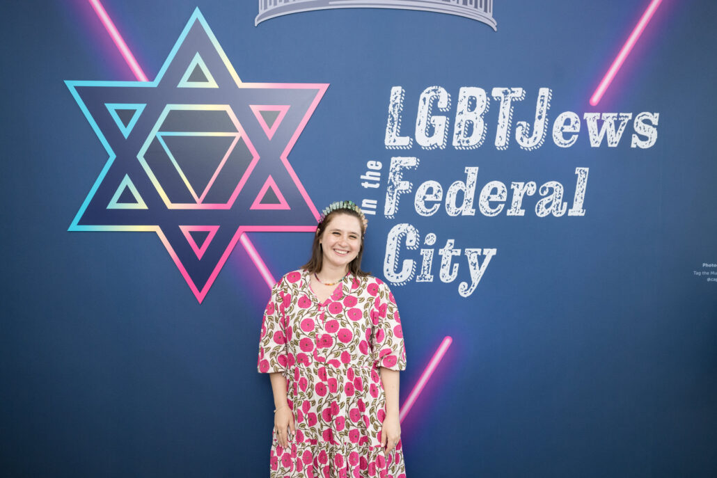 Hally in front of a display for the Capital Jewish Museum's LGBTJews in the Federal City exhibit.