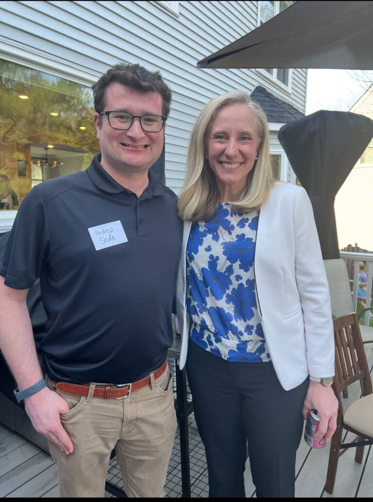 Andrew in business casual standing with a blonde woman.