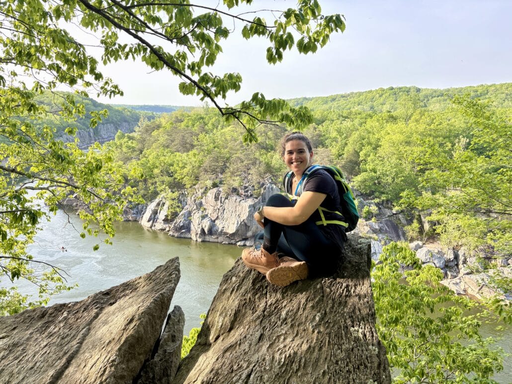 Sophie sits on a rock during a hike.