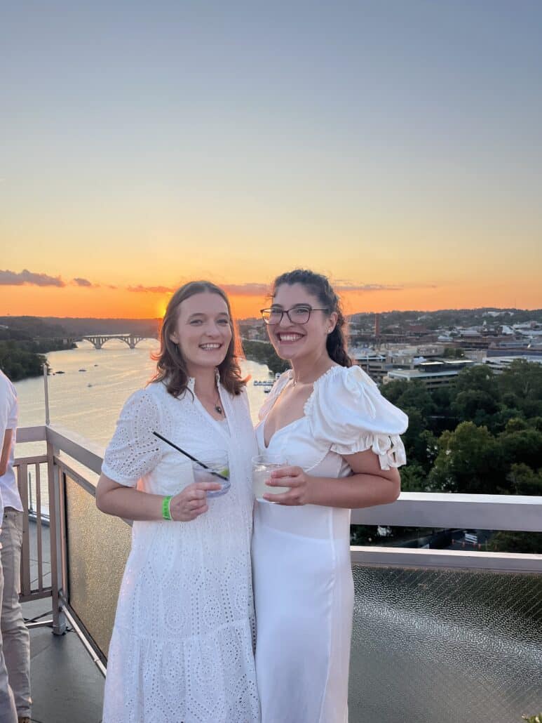 Kate and a friend at sunset in white dresses.