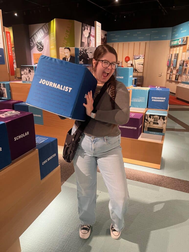 Sigi holding a cube that says "Journalist" at the Capital Jewish Museum.