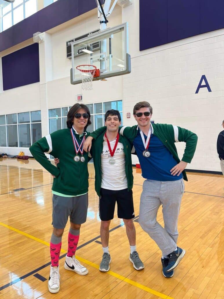 Jake and two friends wearing medals in a gym.