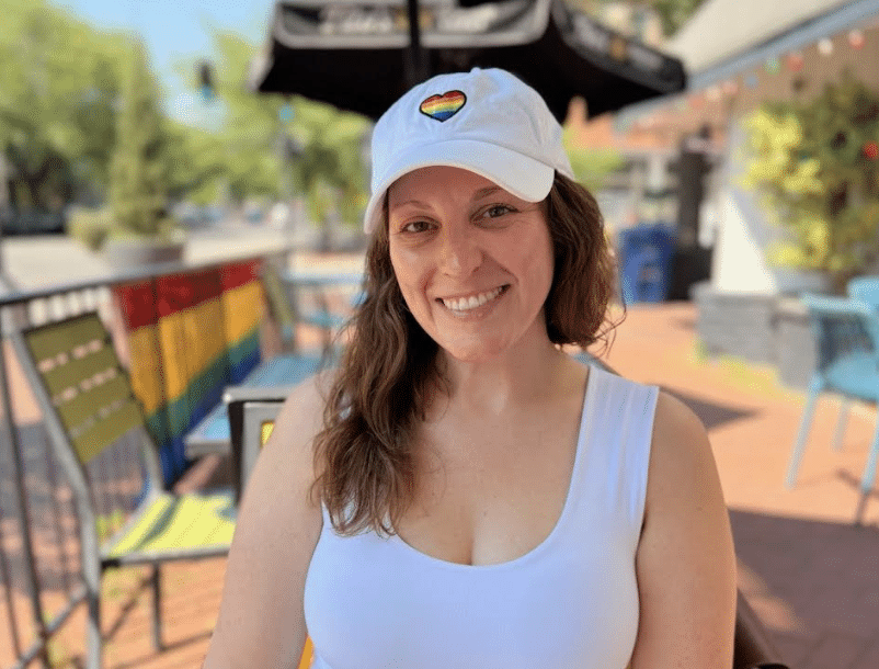 Jamie in a white hat with a rainbow heart.