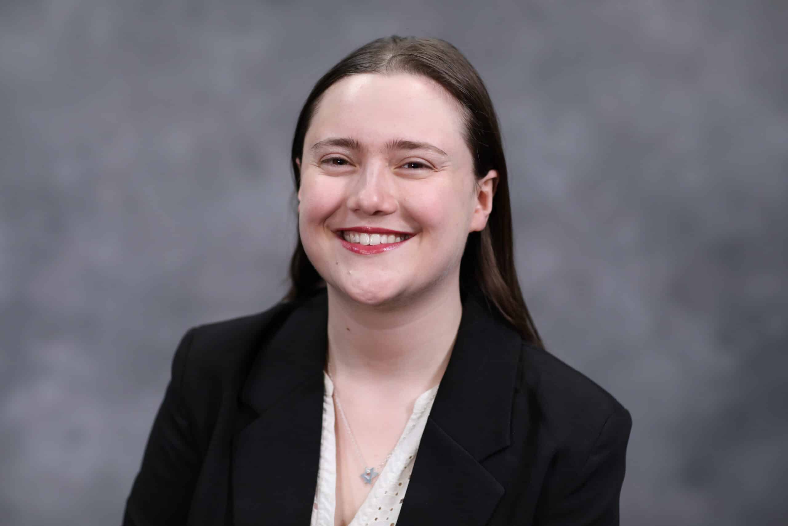 A headshot of Samantha in a black blazer.