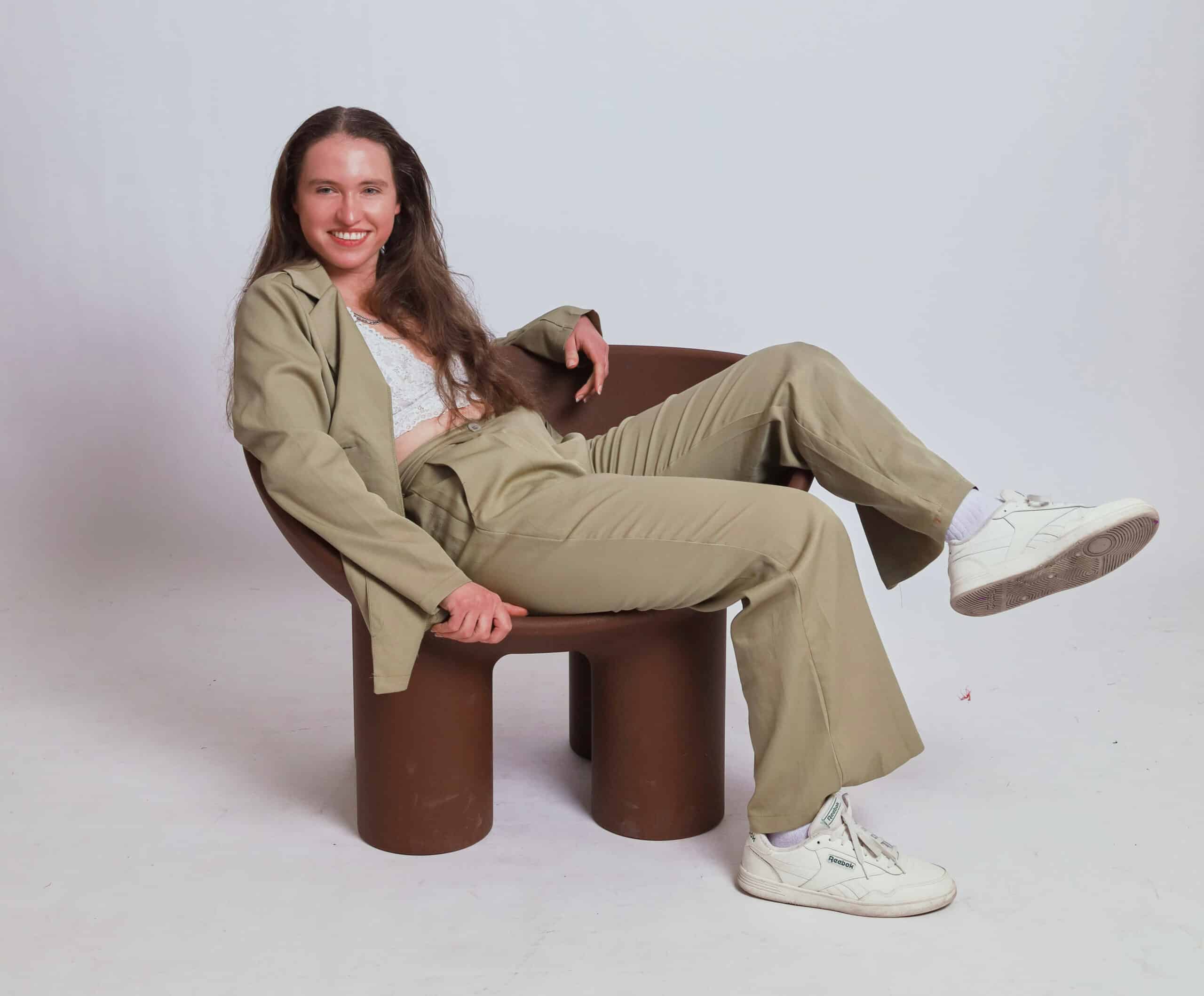 Aimee reclines in a beige suit.