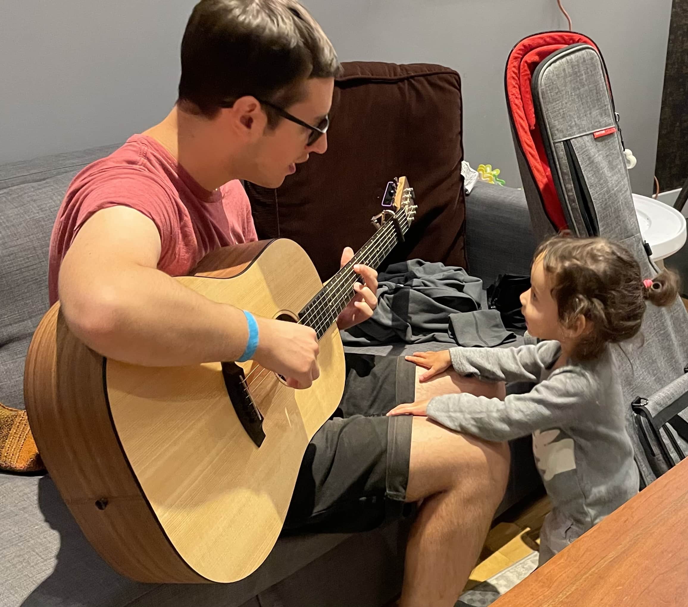 Sam playing a guitar for a child.