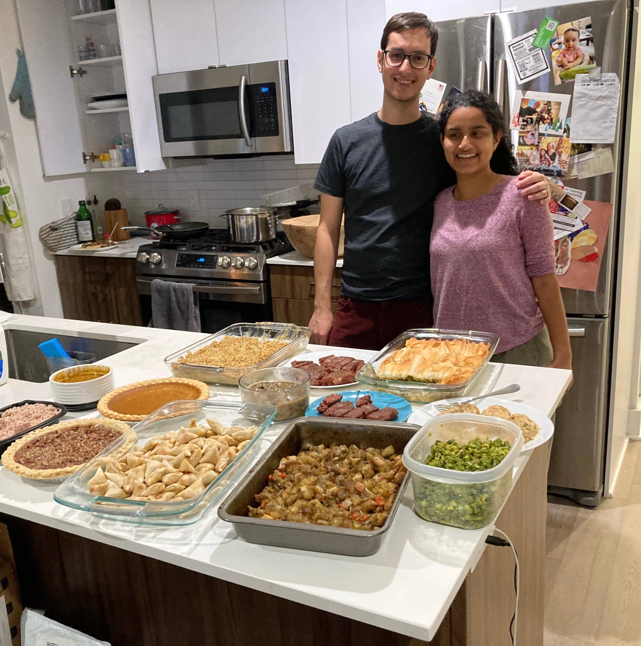 Sam and a woman in a purple shirt cooking.
