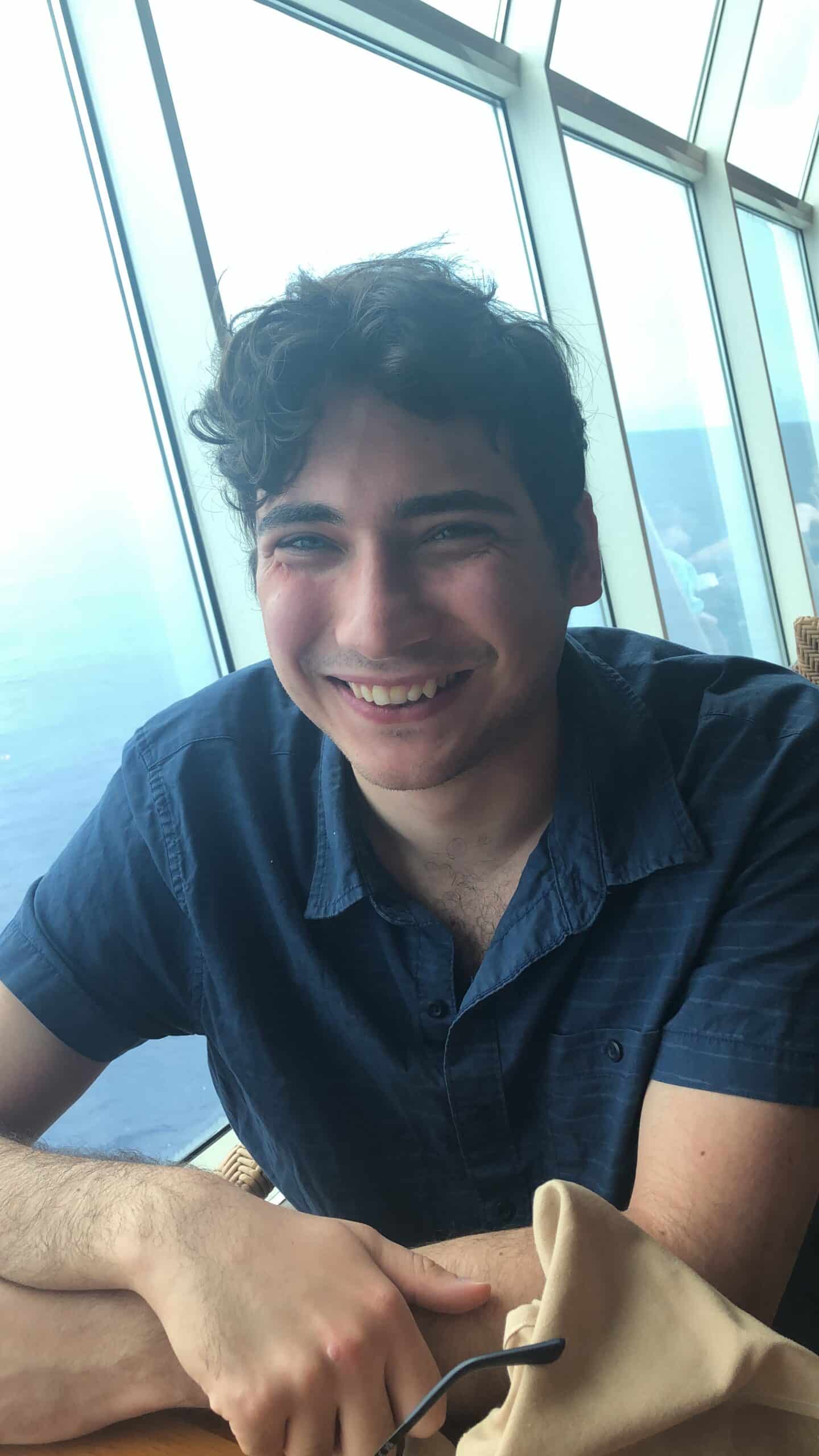 Sam near a window, smiling.