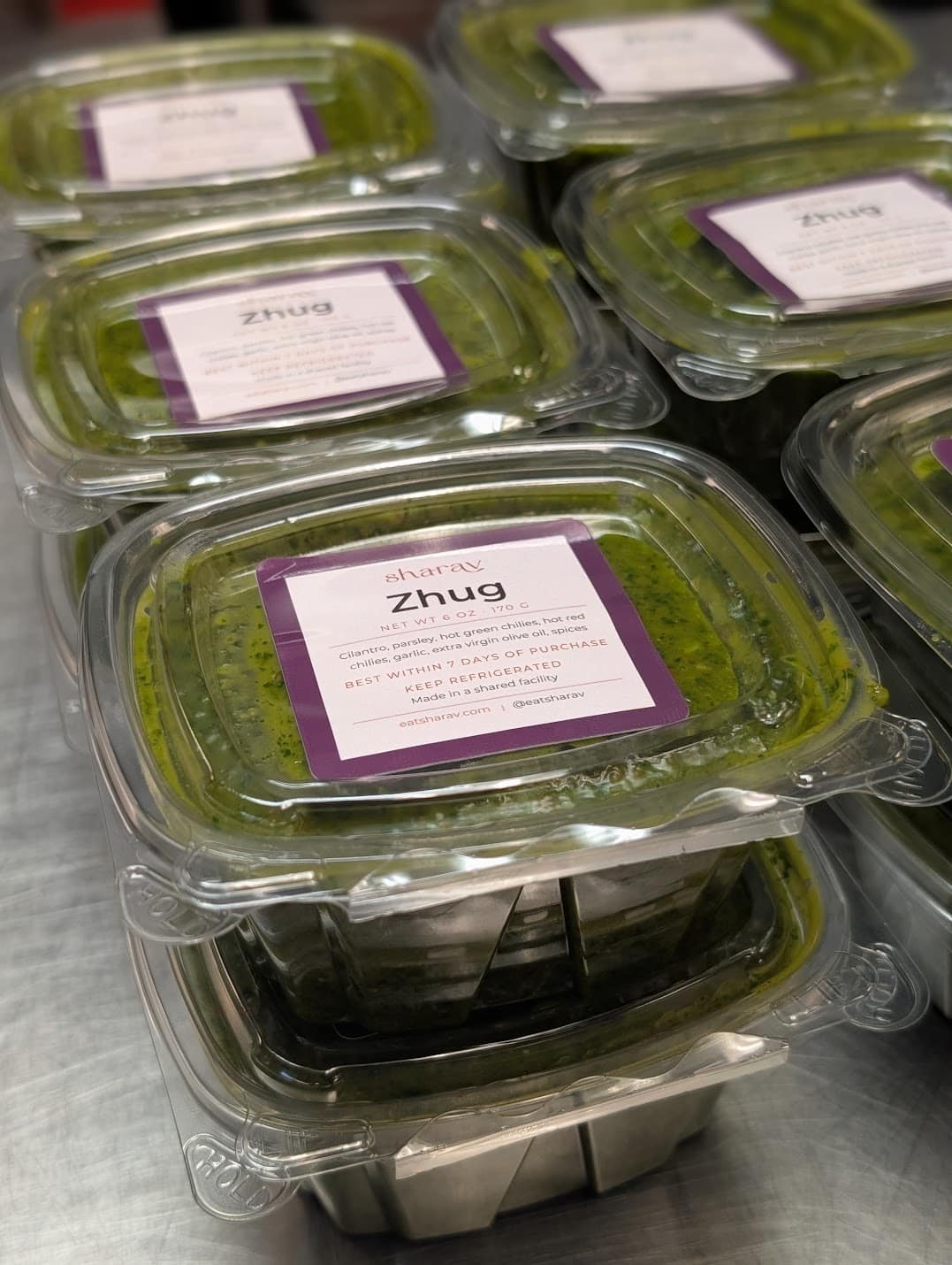 Zhug. Green sauce in plastic containers.
